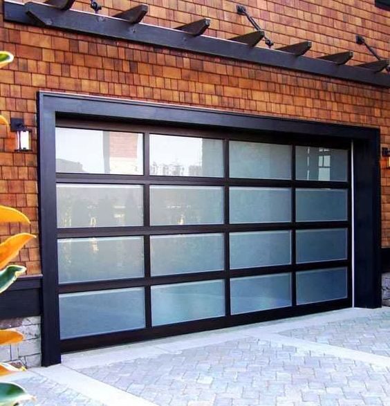 Contemporary black-framed garage door with frosted glass panels, set against a cedar shake or wood siding home exterior.