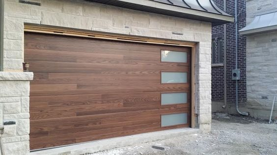 Rich, horizontal wood-grain garage door with frosted glass panels. Mastercraft Garage Door Service, LLC offers custom designs.