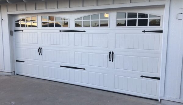 Modern white carriage-style garage door with decorative hinges.