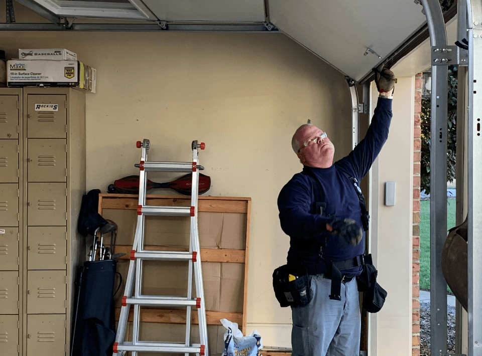 Garage Door Inspection and Maintenance Service Technician inspecting garage door track and hardware inside residential garage